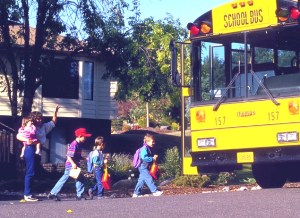 mother watching kids board school bus